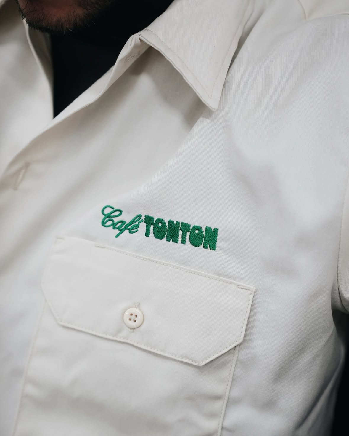 The green TonTon logo embroidered on a cream work shirt