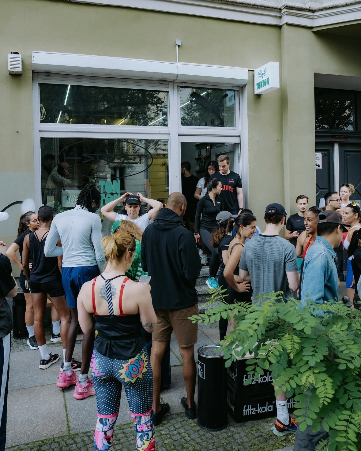 The crowd of the PUMA H-Street Community Run on the pavement outside the Café TonTon sign.
