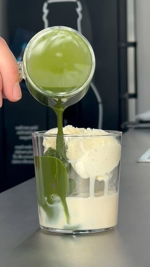 Matcha poured over a scoop of vanilla ice cream in a glass