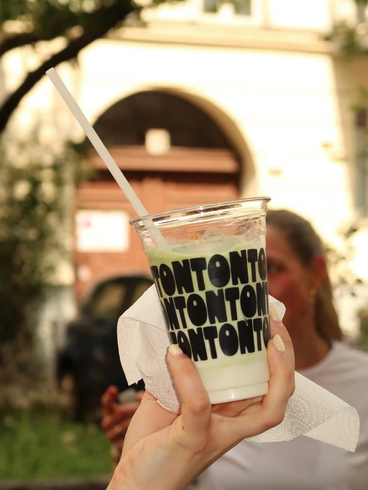 An iced matcha in a TONTON cup, held up after the Vitamin Well community run.