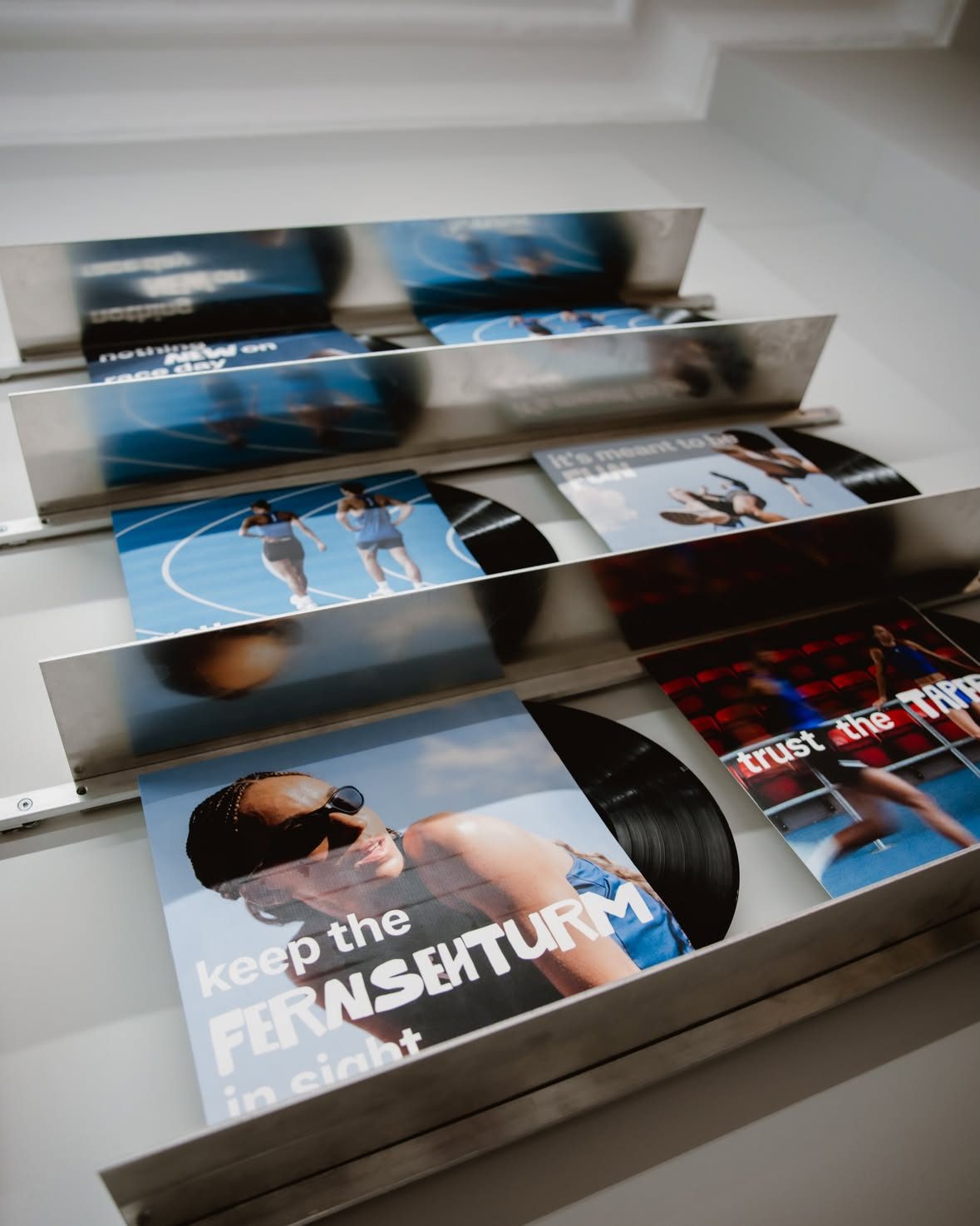 Records in printed sleeves on a steel rack at the Runna run and listening session.